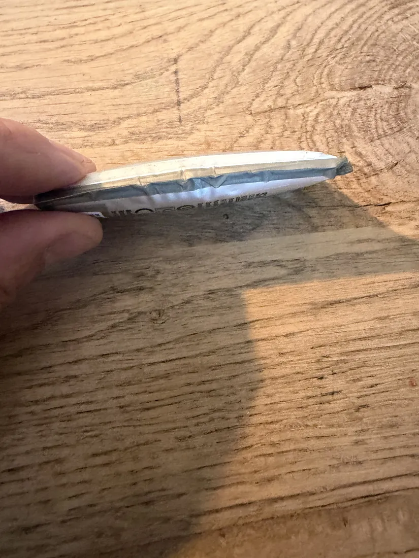 Opgezwollen lithium-ionaccu van een telefoon, van opzij vastgehouden, duidelijk bol staand