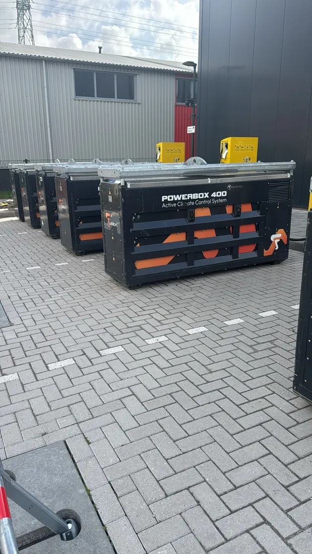 Rij mobiele batterij-laadeenheden op een bedrijfsterrein, klaar om opgehaald te worden