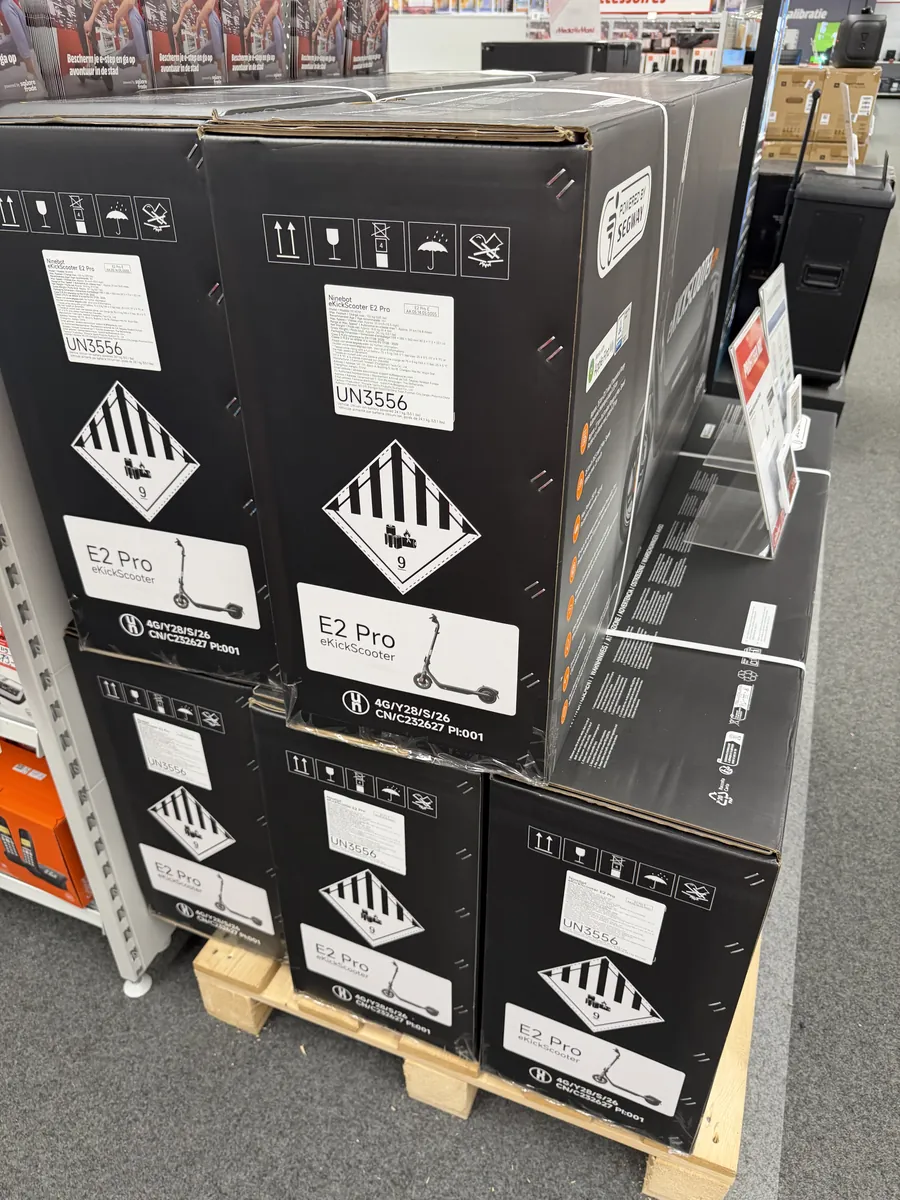 Pallet met dozen elektrische steps in een winkel, elk met het opschrift UN3556 en gevaarsetiket 9A